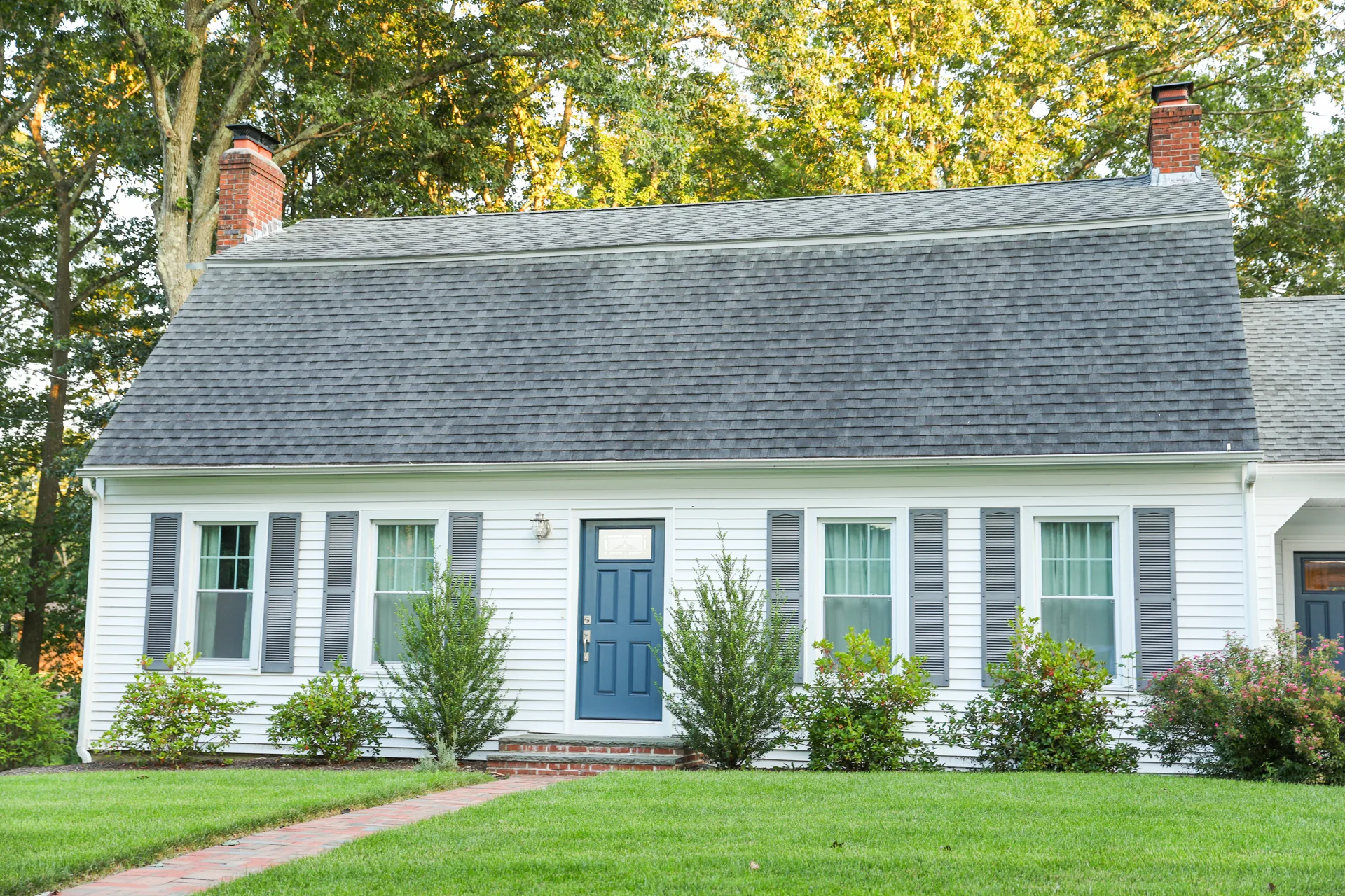 Residential exterior with refreshed roofline, shutters, and front entry landscaping